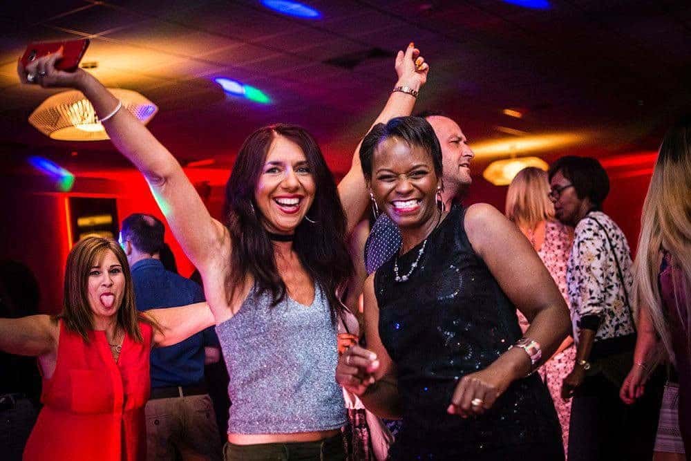 Guests dancing at a work party under red uplighting