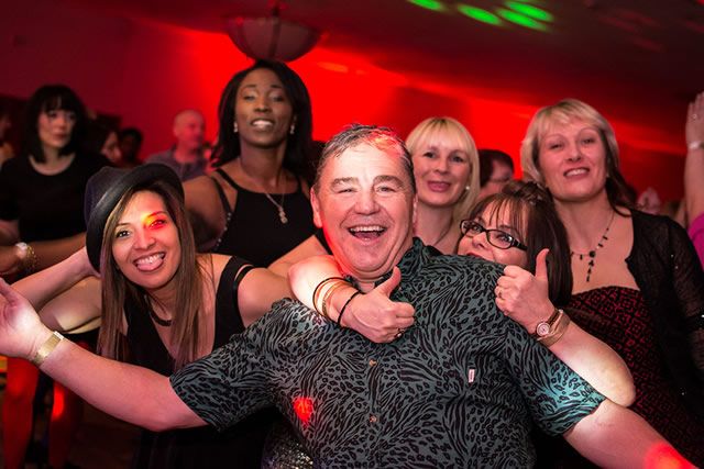 Guests dancing and laughing under red lights