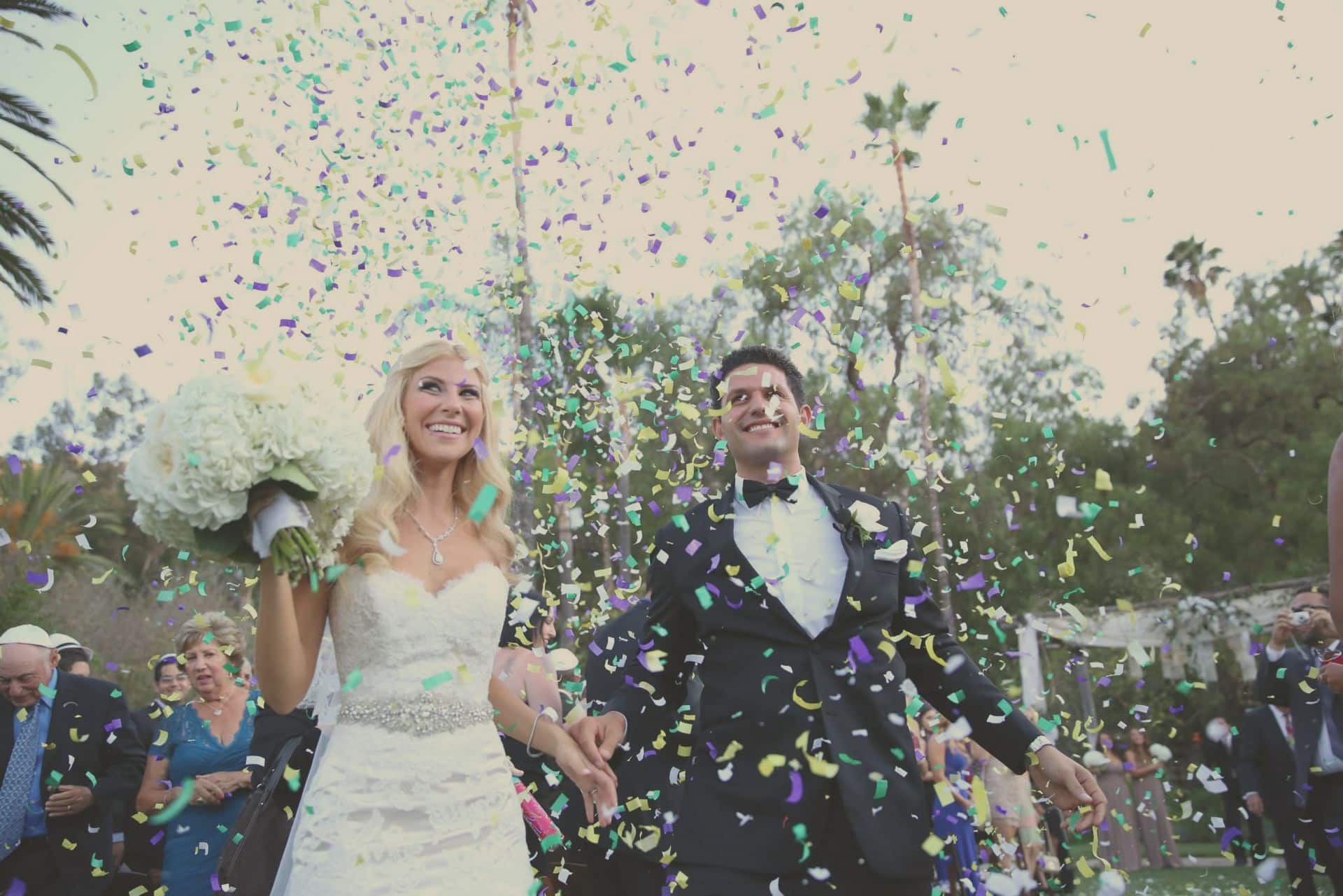 Couple walking through a confetti shower outdoors