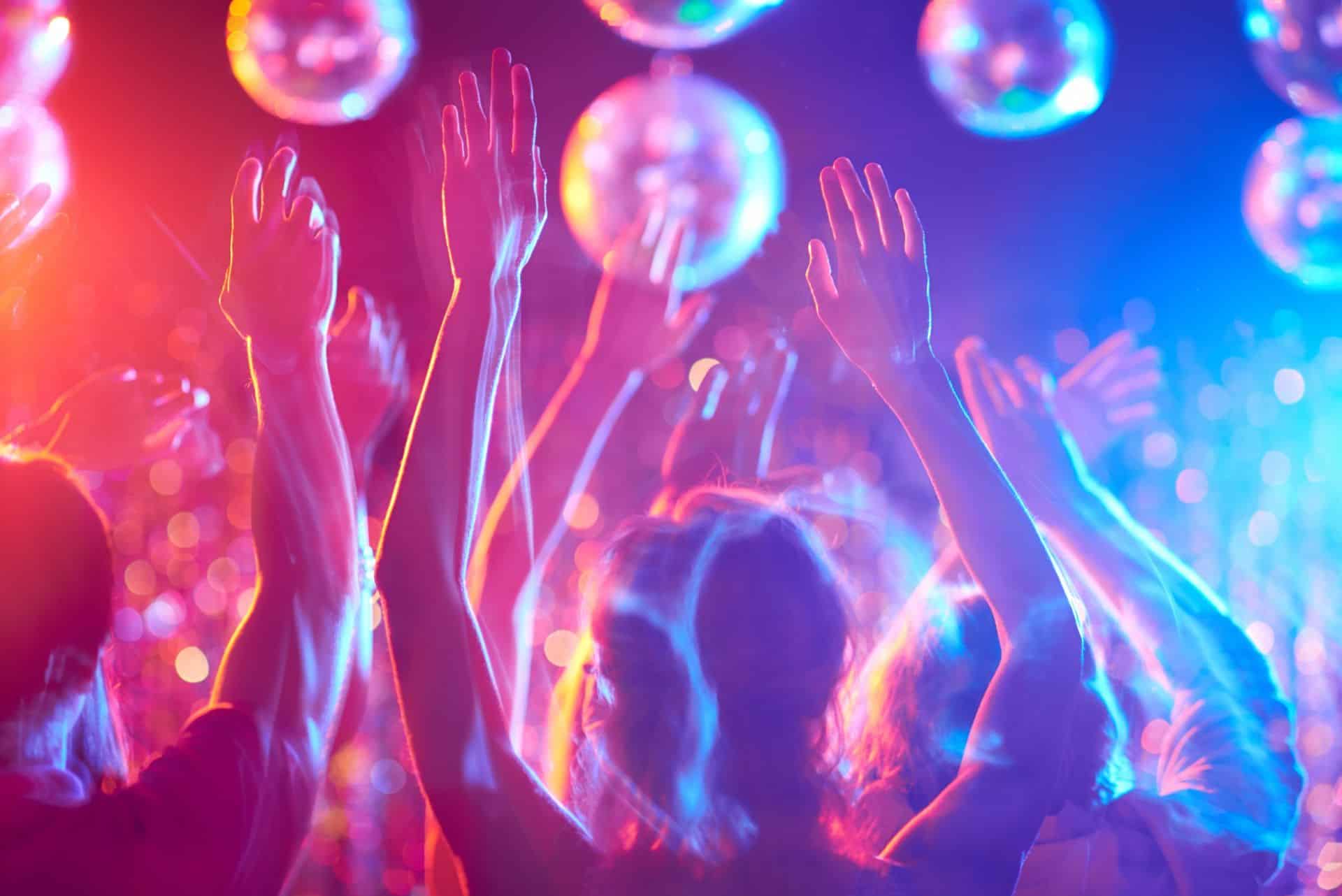 Hands in the air under coloured disco lights